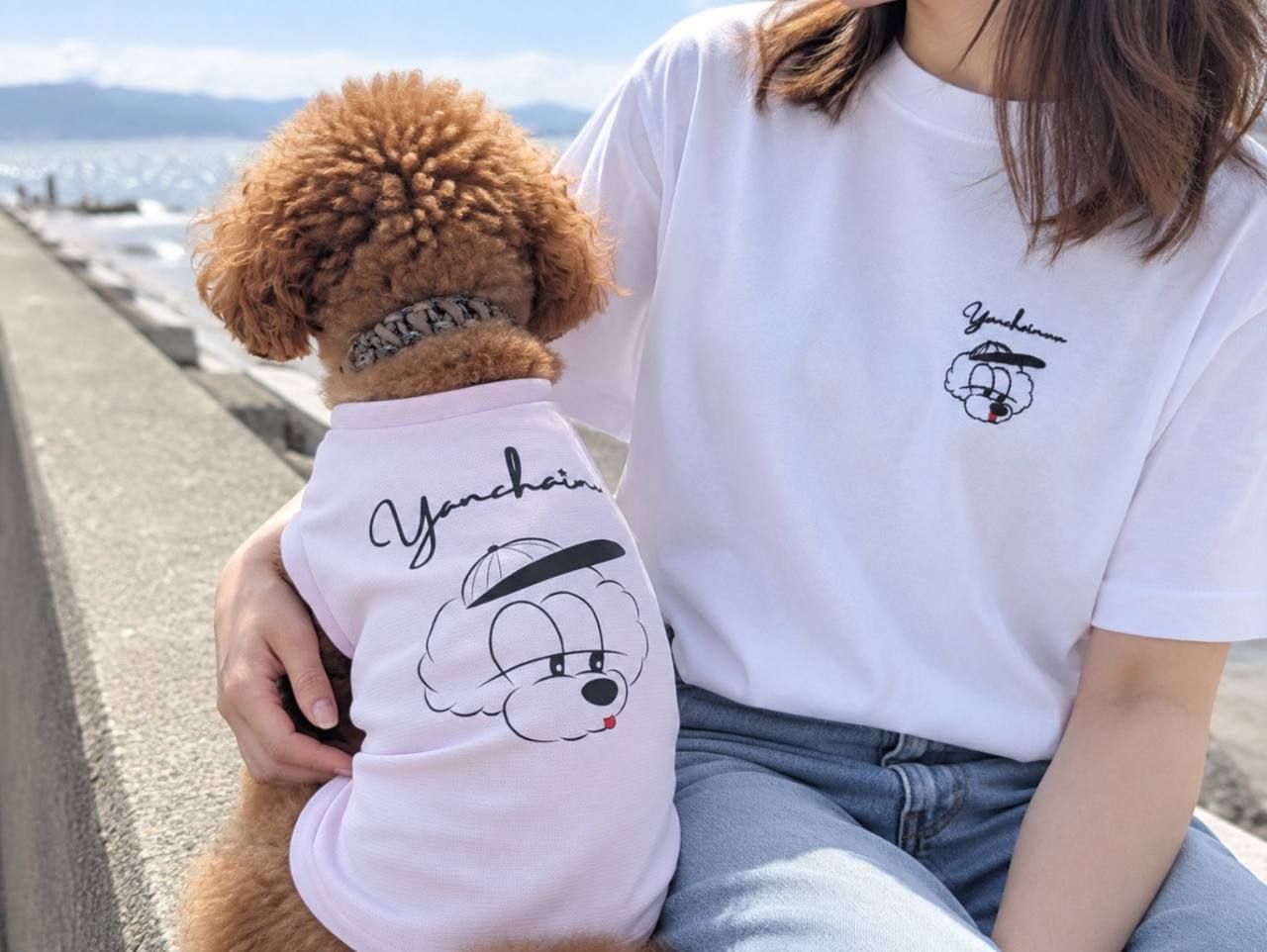 海辺でおそろいのウェアを着る飼い主と愛犬