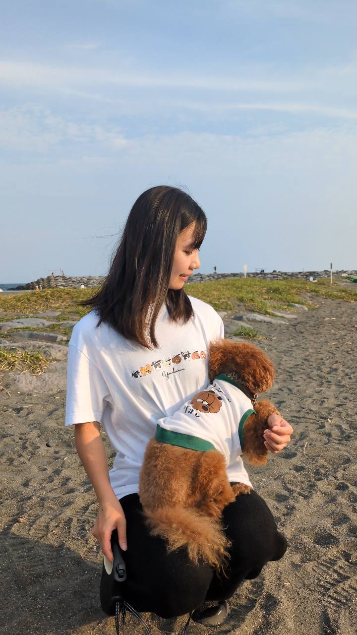 海辺でおそろいのウェアを着る飼い主と愛犬