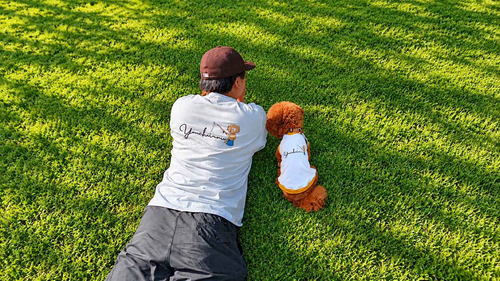芝生でおそろいのウェアを着る飼い主と愛犬